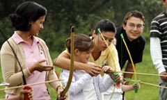 A Disney Cast Member helps a little girl nock an arrow during a family archery lesson.