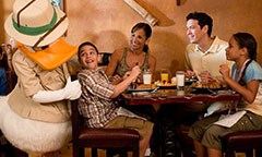 Donald Duck in safari shirt and hat visits with family of four during dinner